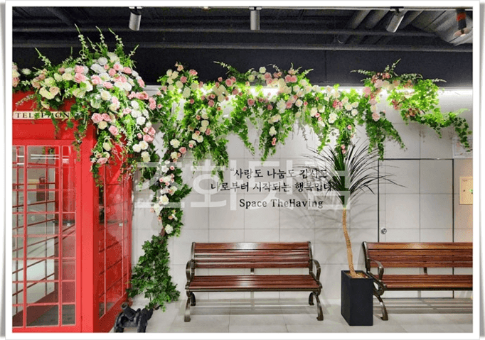 세종시 글린정원 세종점 — 빨간 전화부스 옆 벤치 위로 꽃넝쿨이 드리워진 포토존 좌석 전경