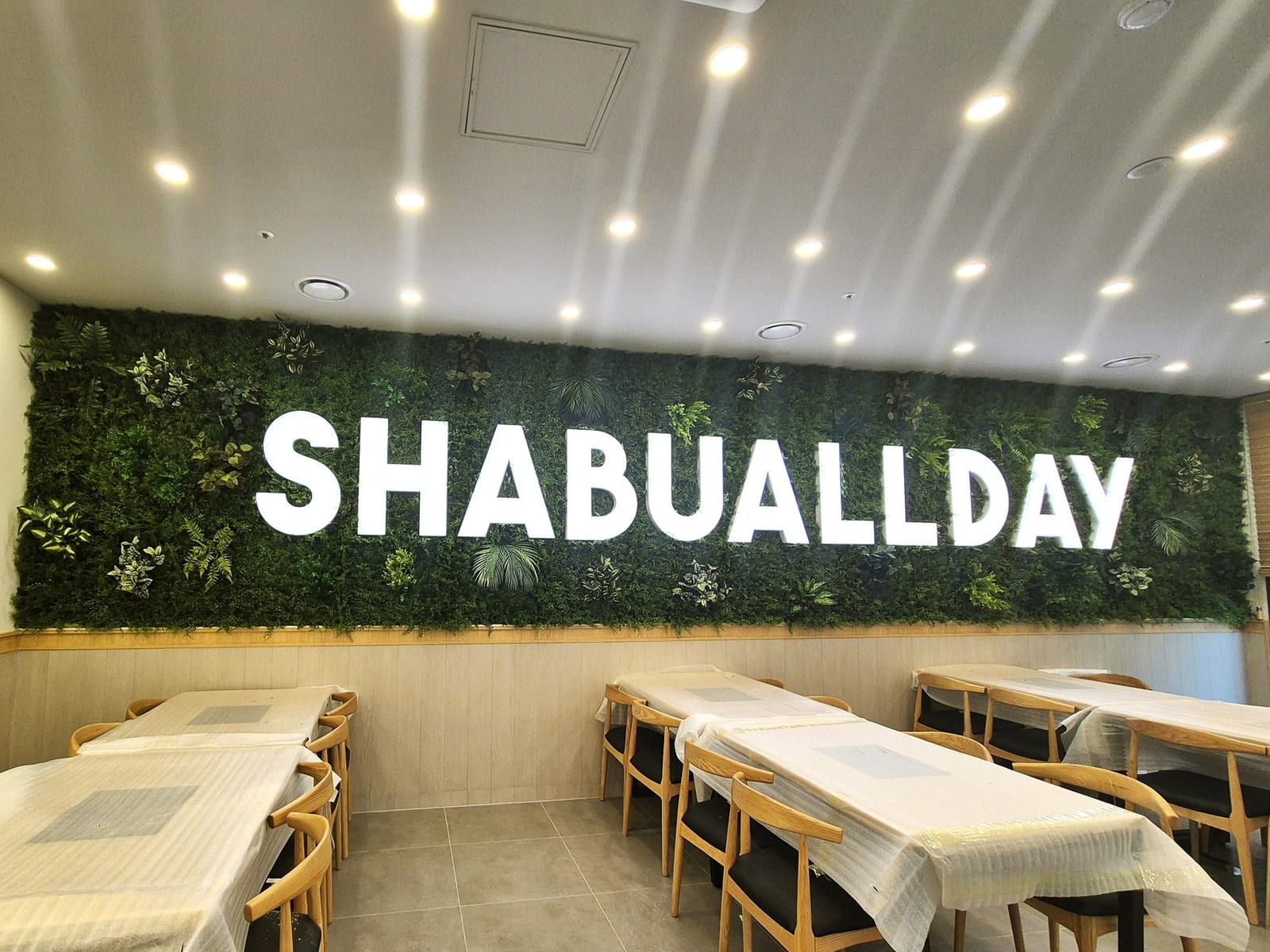 광명시 샤브올데이 — 이끼 질감 그린월 위에 또렷하게 읽히는 SHABUALLDAY 흰 입체 로고