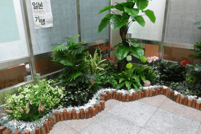 서울 무학중학교 — 곡선 화단을 따라 두른 통나무 경계석과 붉은 꽃 인조식물 디테일
