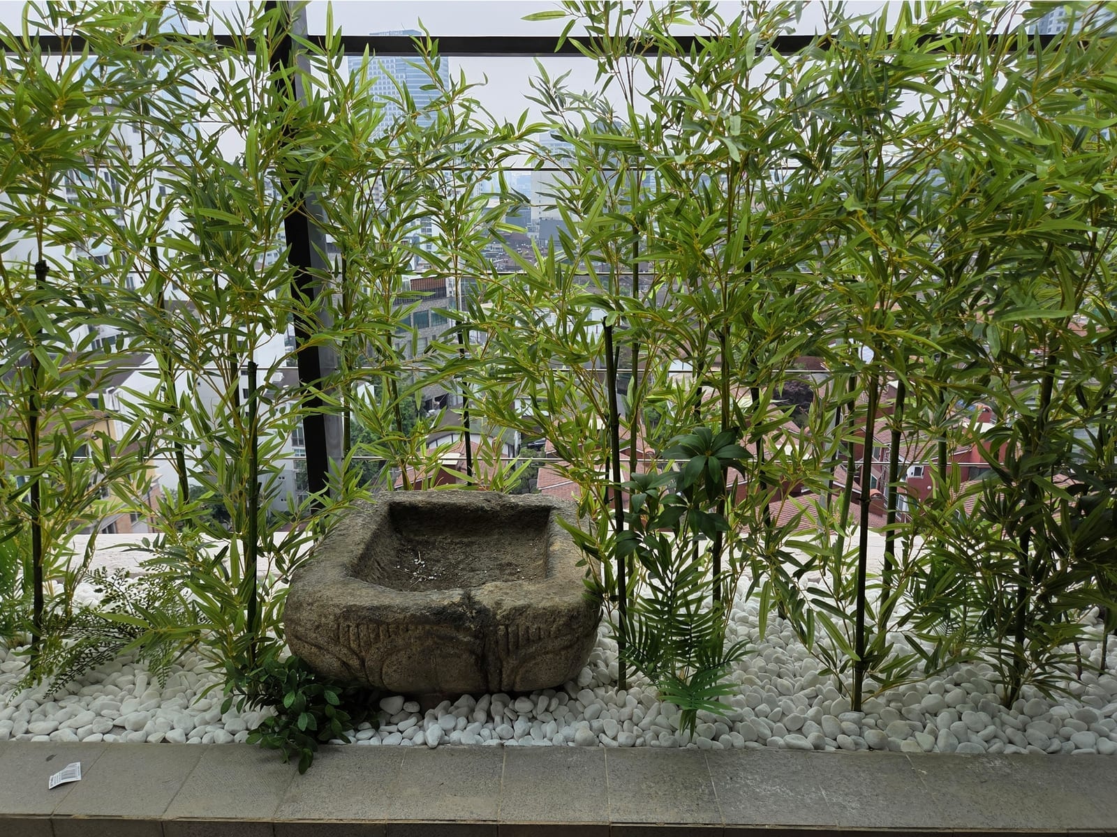 삼성동 주택 베란다 — 인조 대나무 사이에 자연석 수반을 놓고 둘레를 흰 자갈로 마감해 일본식 정원처럼 연출한 모습