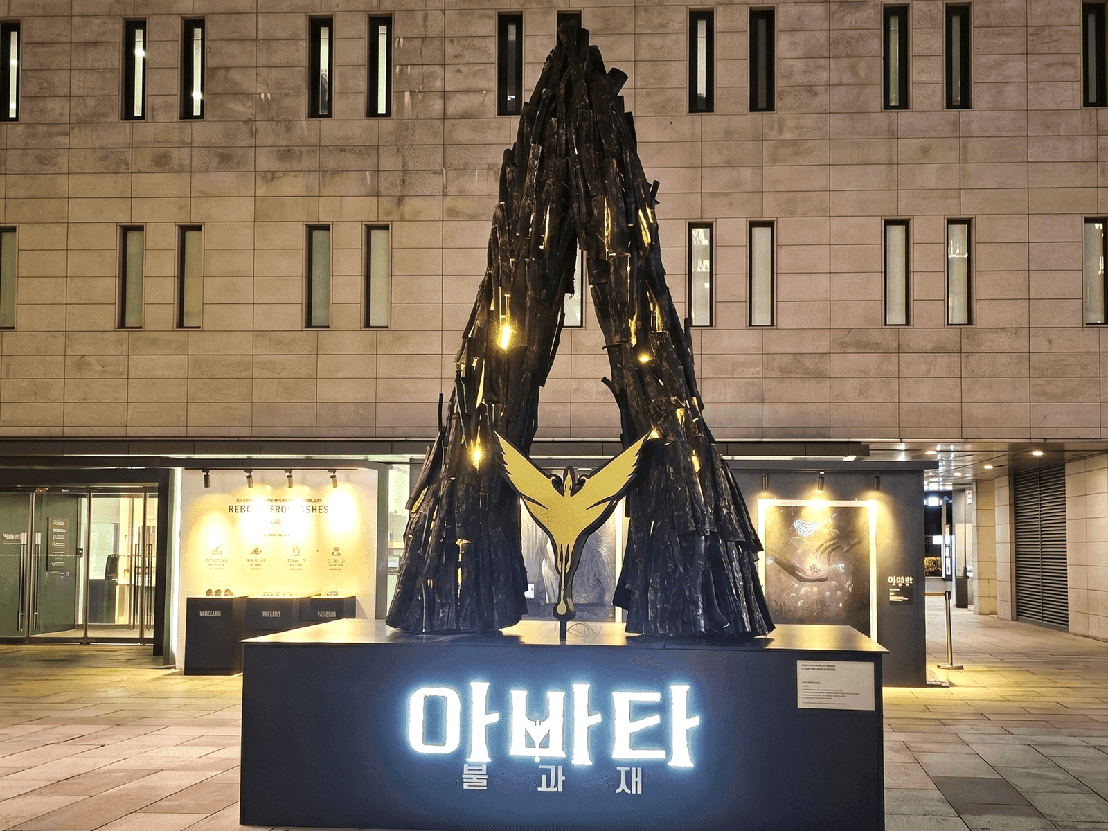 서울 세종문화회관 — 그을린 넝쿨나무를 엮어 두 나무가 마주 솟은 거대 A자 랜드마크 조형물, 밤 조명